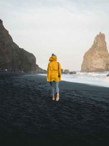photo of person walking along seashore